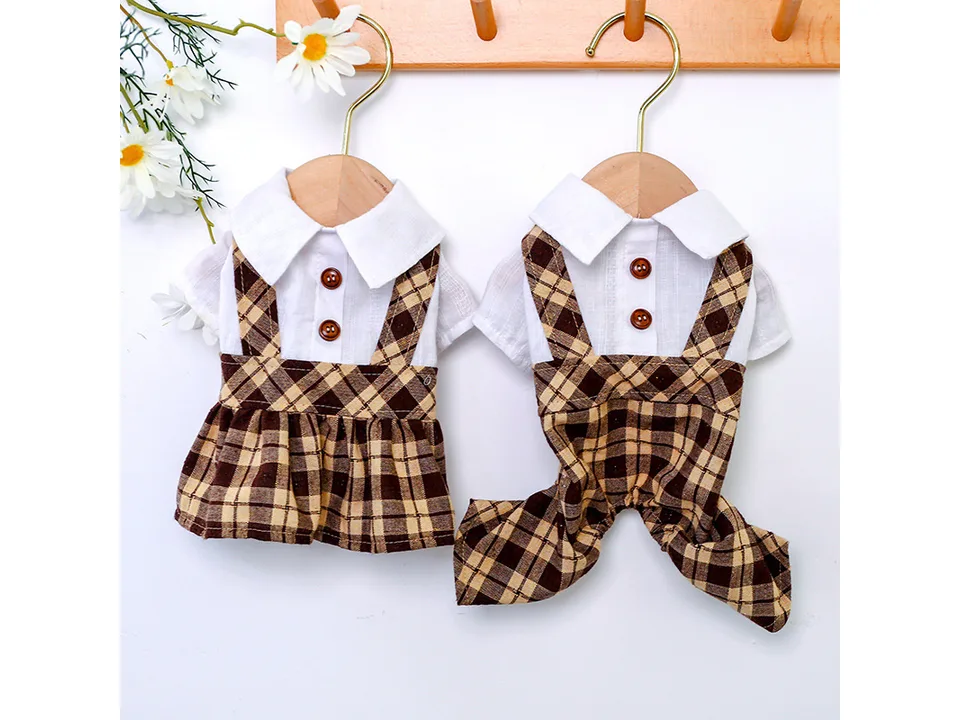 Two pet outfits, a dress and a jumpsuit, hanging on wooden hangers.
