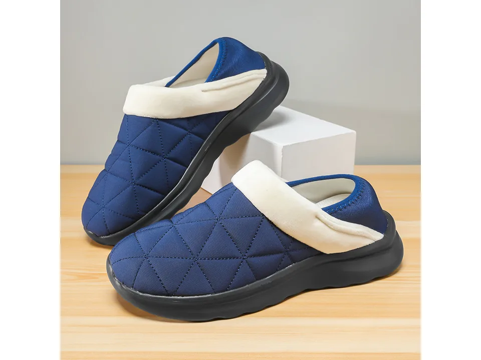 Pair of blue quilted indoor slippers on a wooden surface.