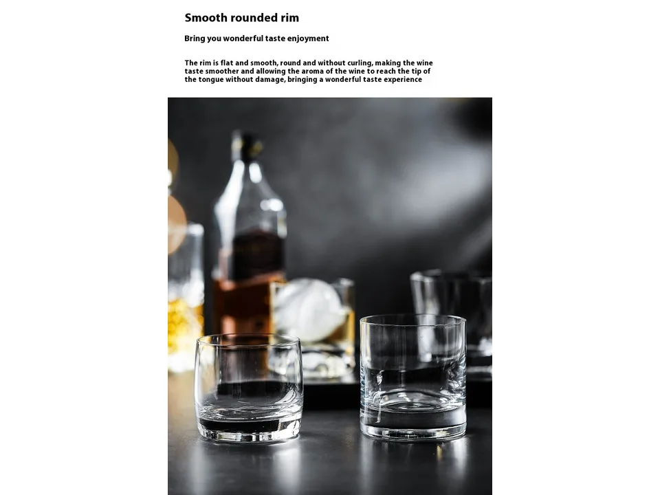 Two crystal whisky glasses on a table with a bottle of whisky in the background.