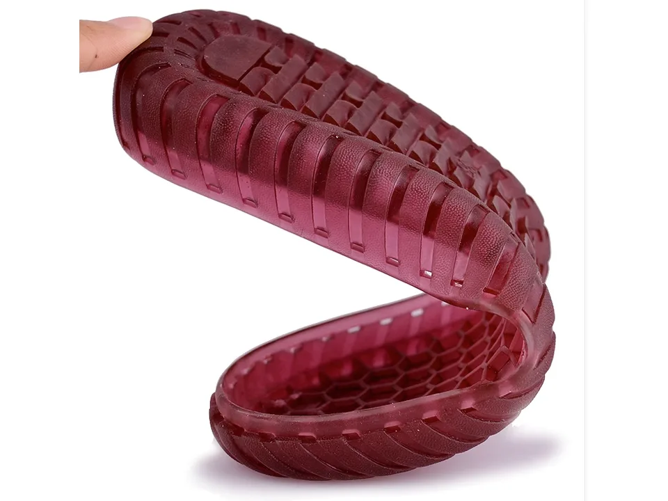 Close-up of a flexible, translucent red shoe sole being bent by a hand.