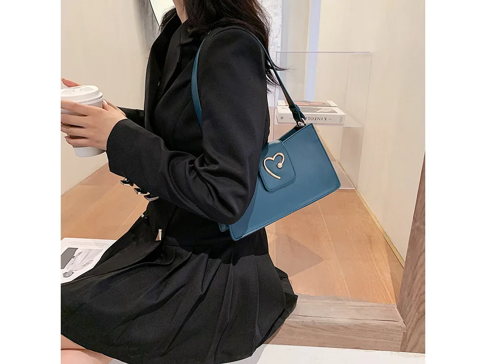 A woman wearing a blue small square shoulder bag over her shoulder.