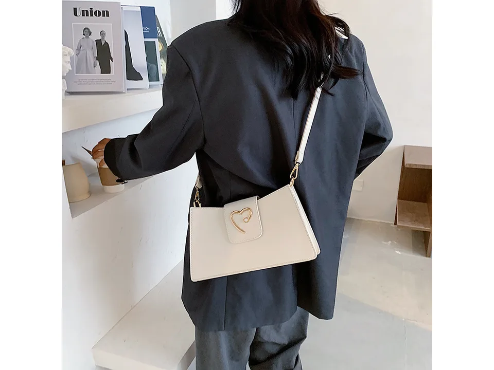 A woman wearing a white small square shoulder bag over her shoulder.