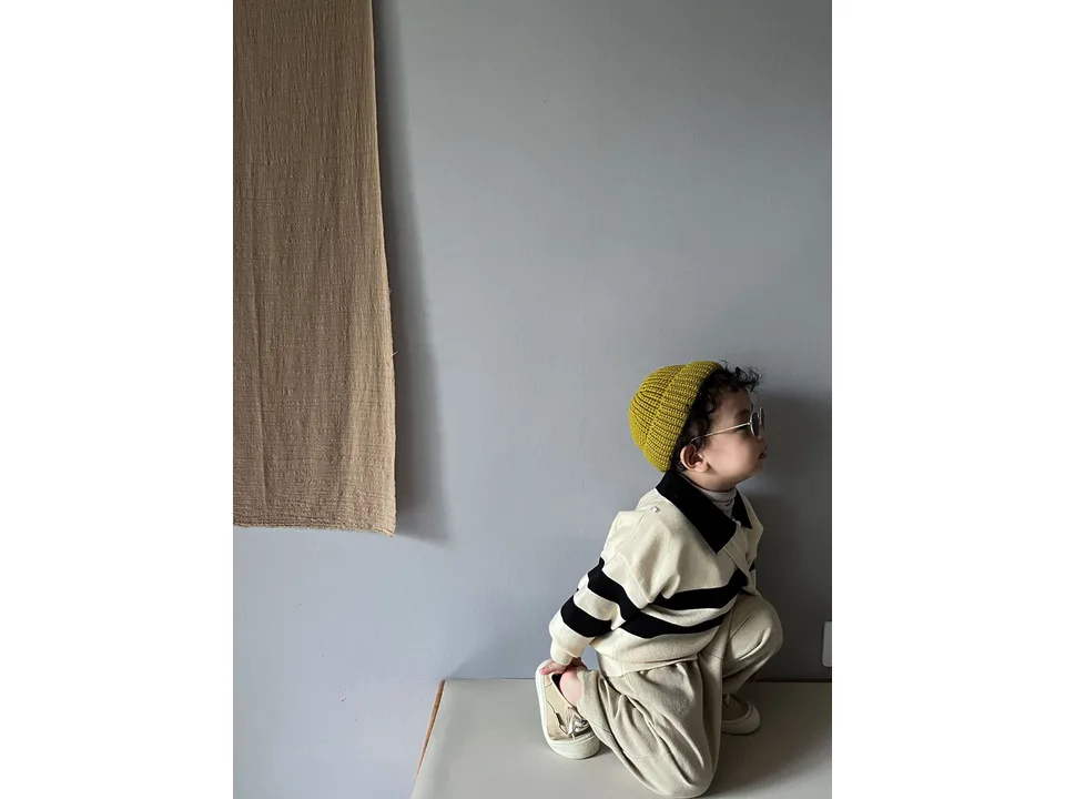 A child wearing the striped knit sweater, viewed from the side.