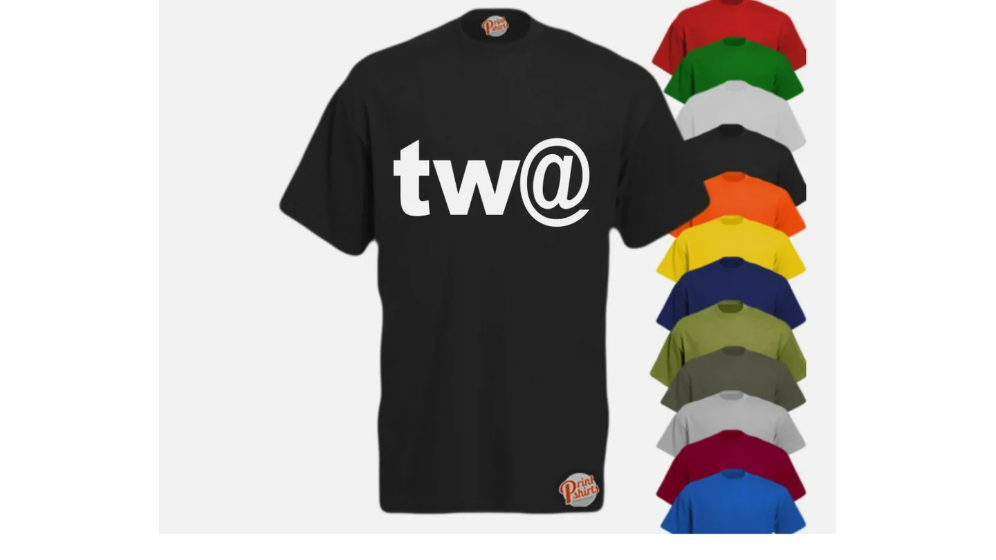 Black t-shirt with 'tw@' graphic print, displayed with a stack of various colored t-shirts.
