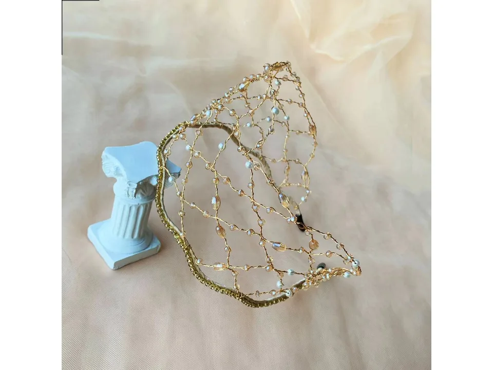Gold-toned beaded hair hoop with crystal accents displayed on a small decorative pillar.