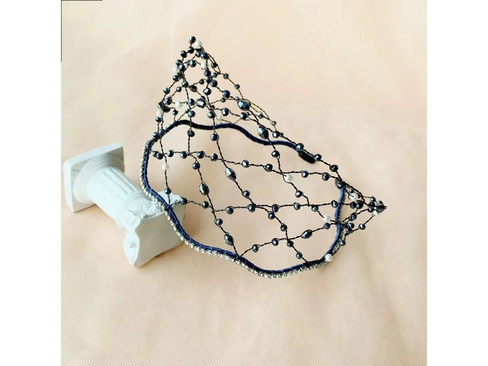 Dark-toned beaded hair hoop with crystal accents displayed on a small decorative pillar.