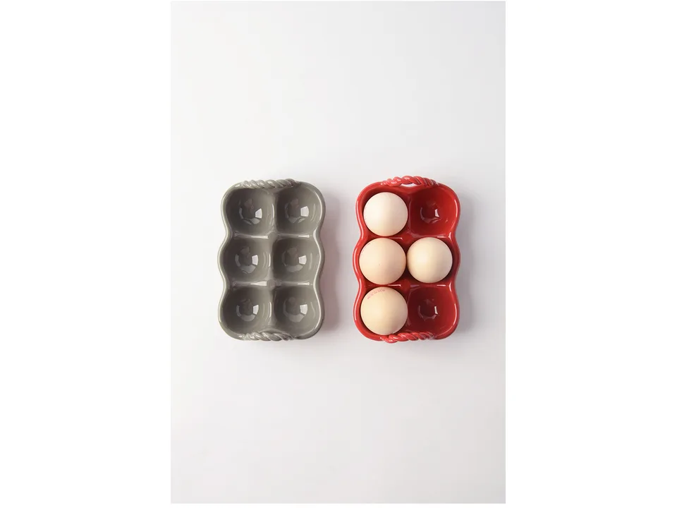 Two ceramic egg trays, one grey and one red, with eggs in the red tray.