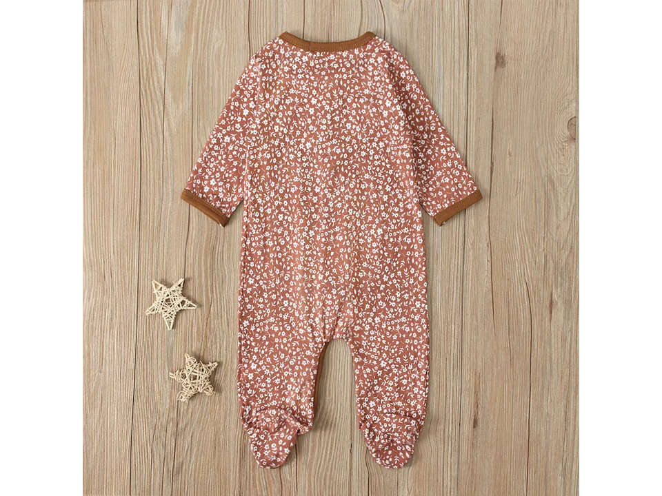 Full view of the floral baby jumpsuit on a wooden background.