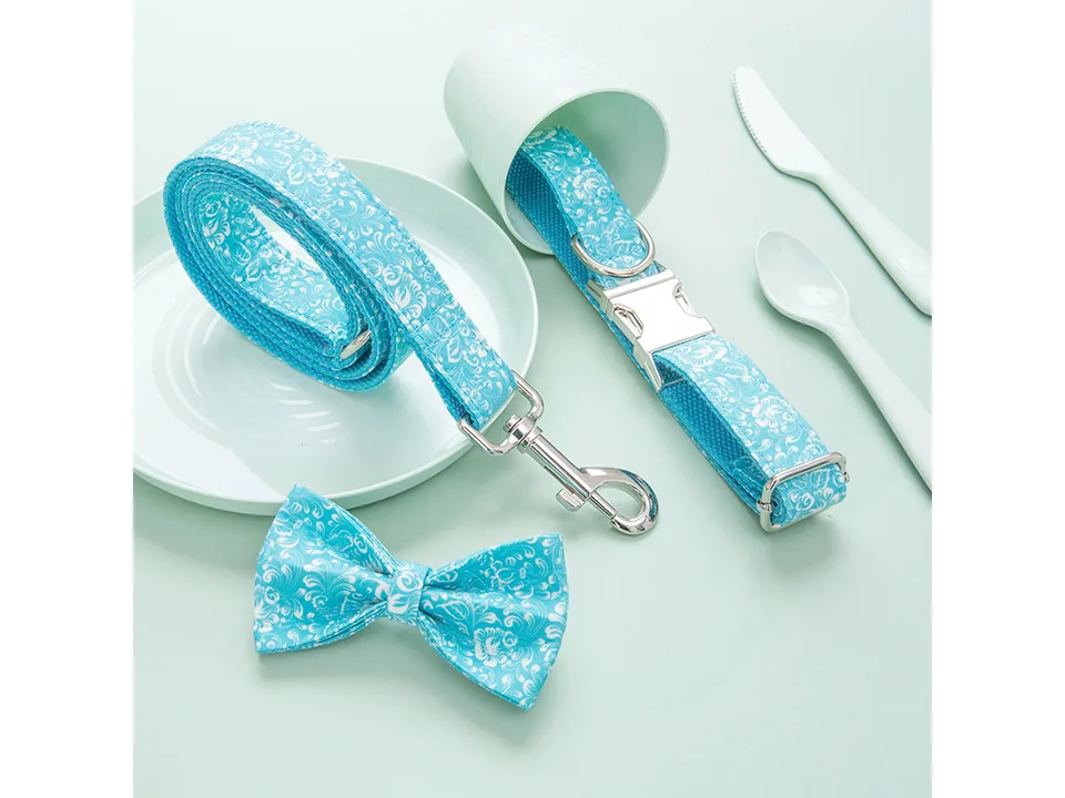 Blue floral dog collar with bow tie and matching leash on a light background.
