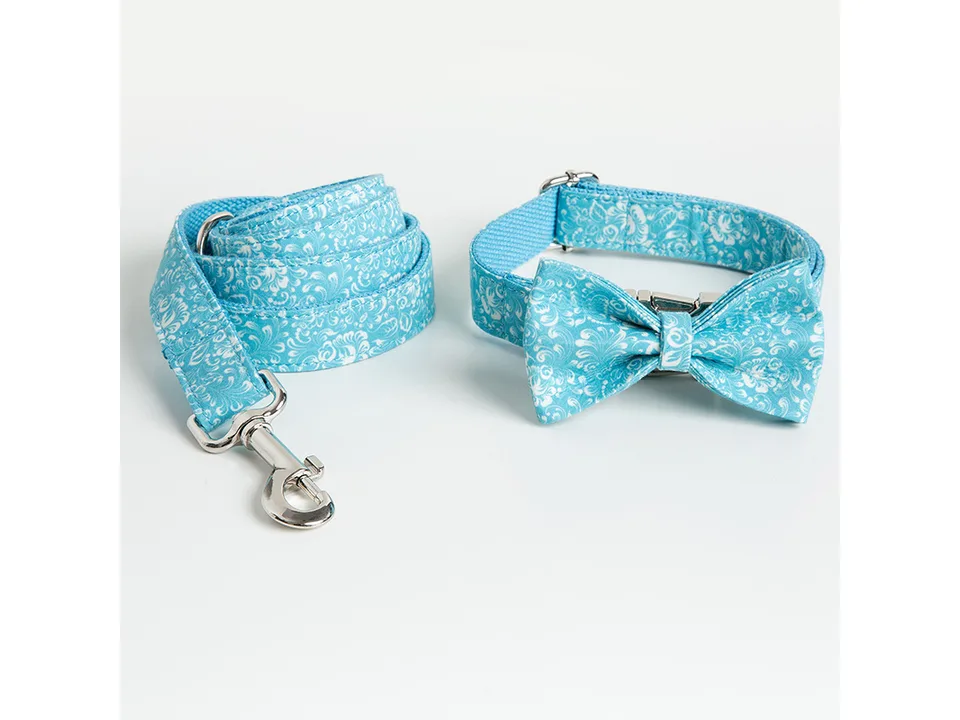 Blue floral dog collar with bow tie and matching leash on a plain white background.
