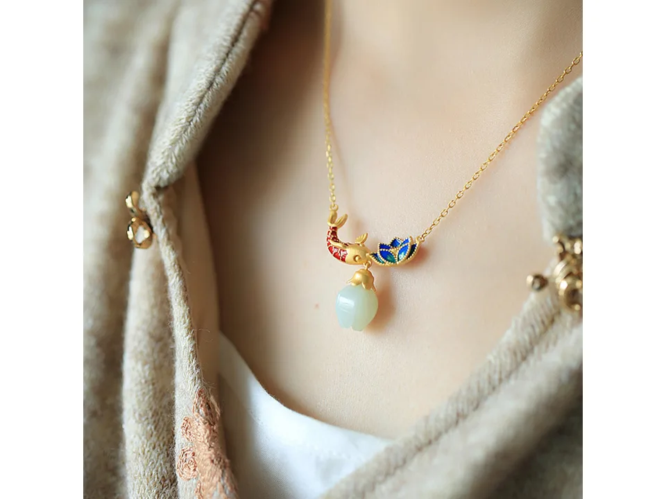 The koi and lotus necklace worn on a person.