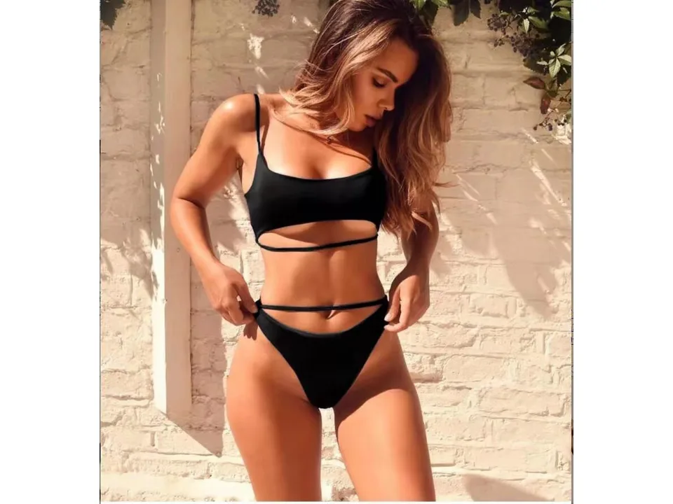 A woman wearing a black two-piece bikini with cutout details.