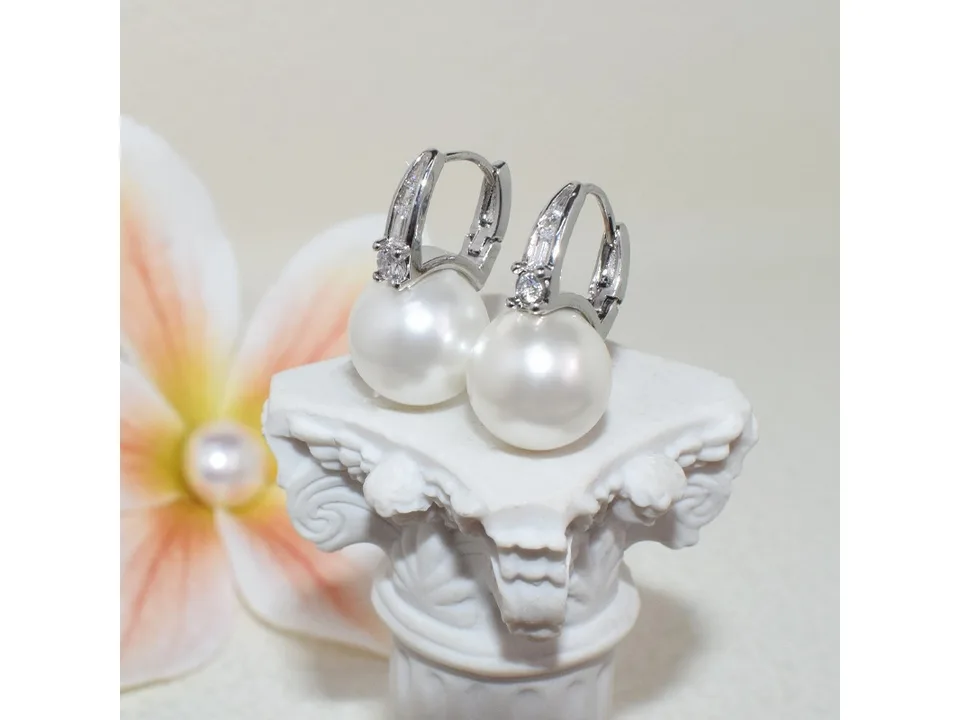 Pearl and zircon hoop earrings displayed on a small decorative pedestal.