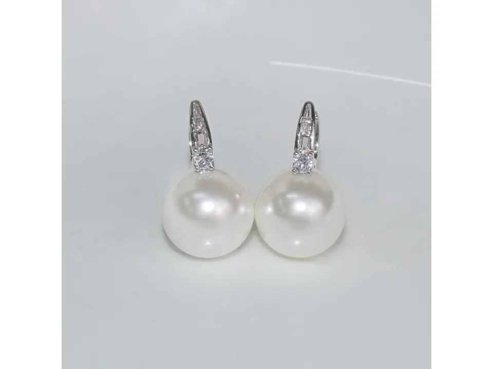 Pair of pearl and zircon hoop earrings on a white background.