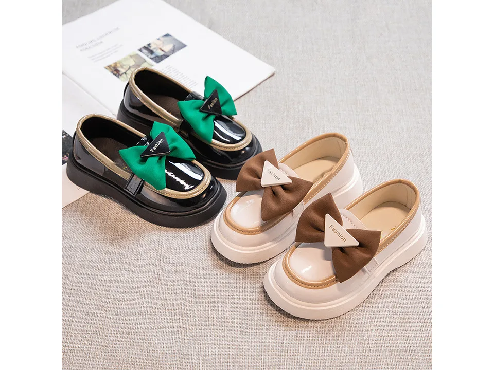 Two pairs of girls' loafers, one beige and brown, one black and green.