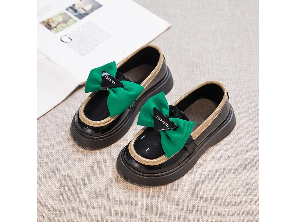 A pair of black and green girls' loafers with bows.