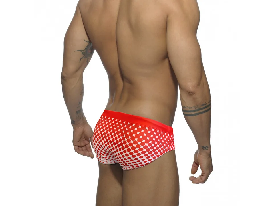 Back view of a model wearing red polka dot swim briefs.