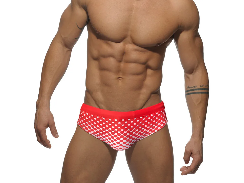 Front view of a model wearing red polka dot swim briefs.
