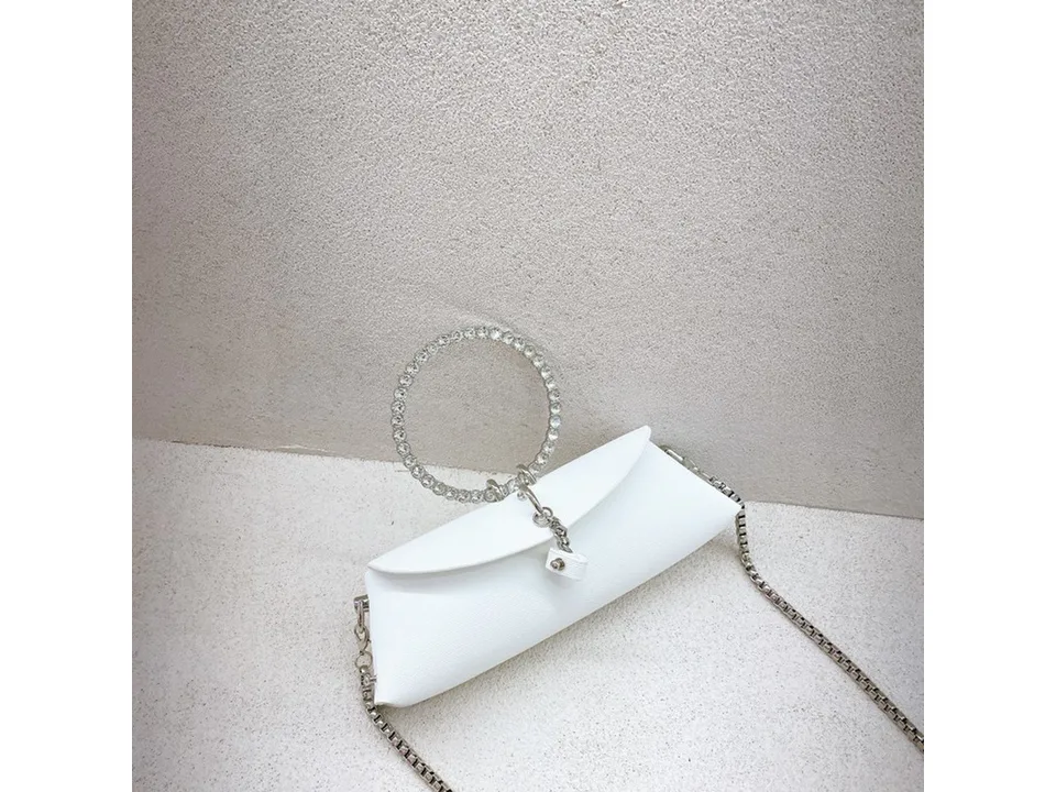 A small white handbag with a rhinestone ring handle and a silver chain shoulder strap.