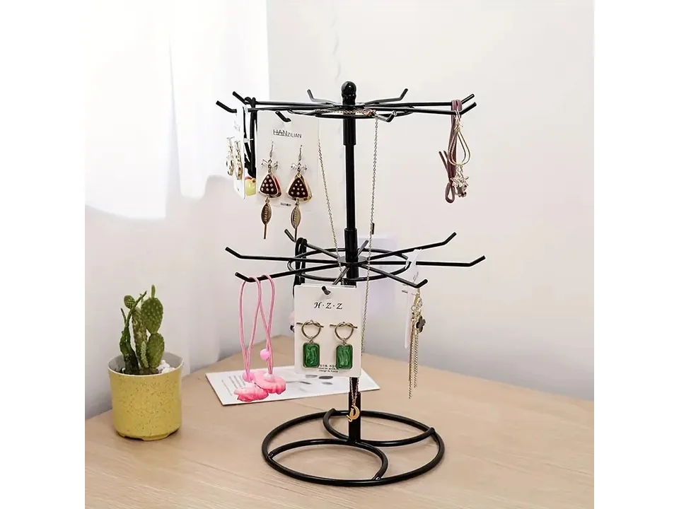 Black two-tier jewelry display stand holding various earrings and necklaces on a wooden table.