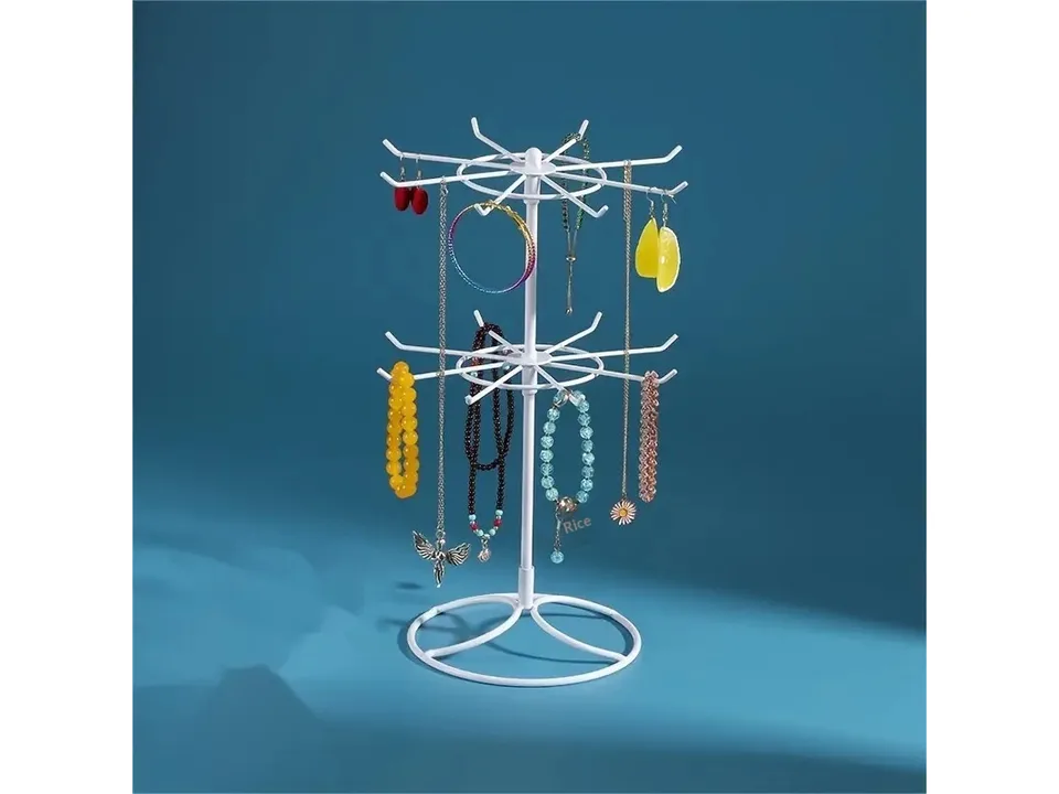 White two-tier jewelry display stand holding various bracelets and necklaces against a blue background.