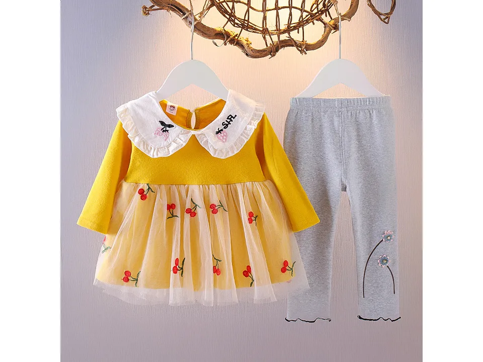 Yellow long-sleeved dress with cherry print and tulle skirt, paired with grey leggings.