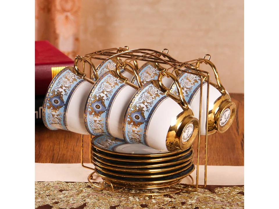 A set of blue and white porcelain coffee cups and saucers displayed on a gold metal rack.