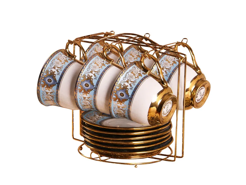 A set of blue and white porcelain coffee cups and saucers on a gold metal rack, isolated on white.