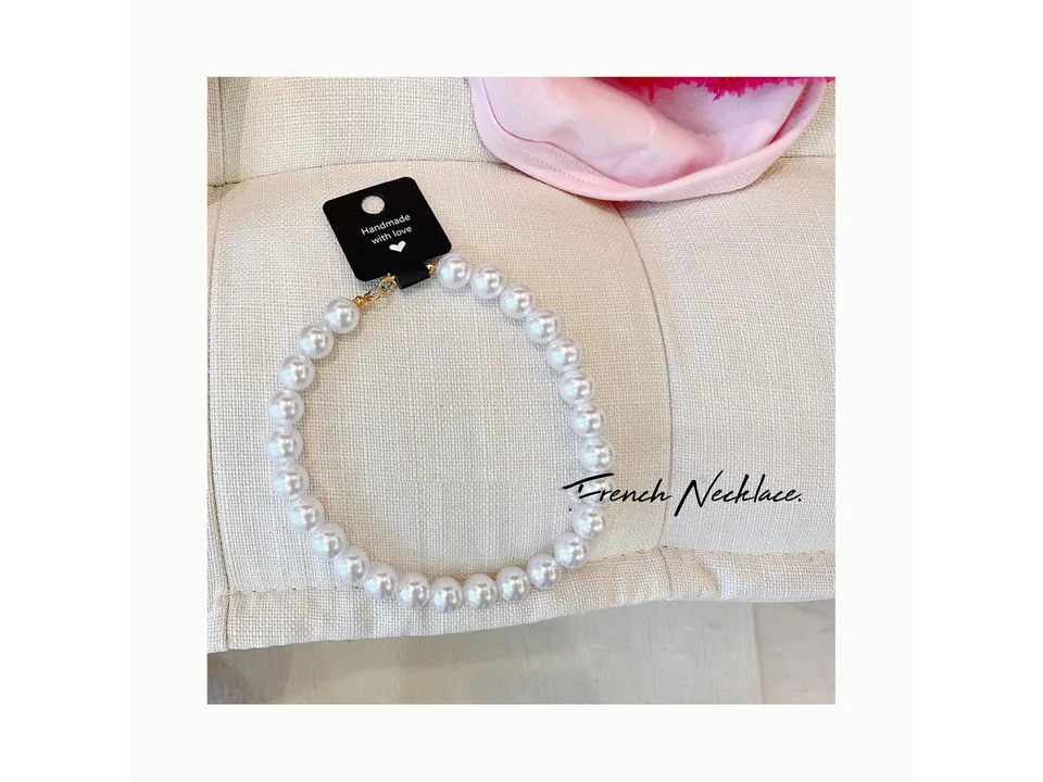 A pearl necklace for pets with a handmade tag.