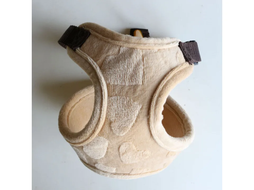 Beige plush dog harness with heart pattern.