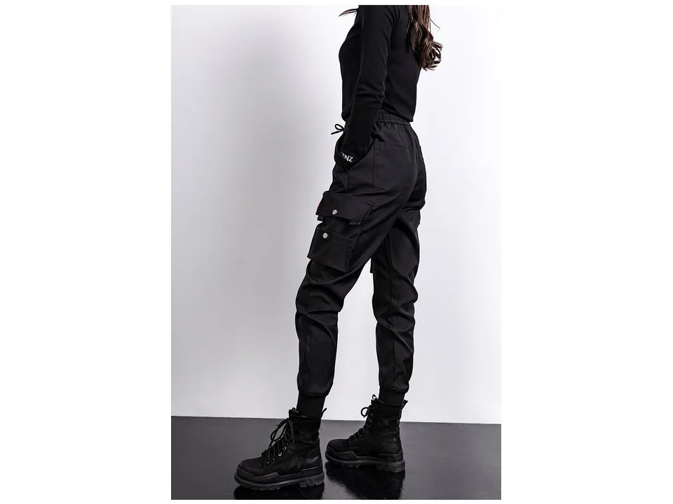 A woman wearing black cargo jogger pants, side view.