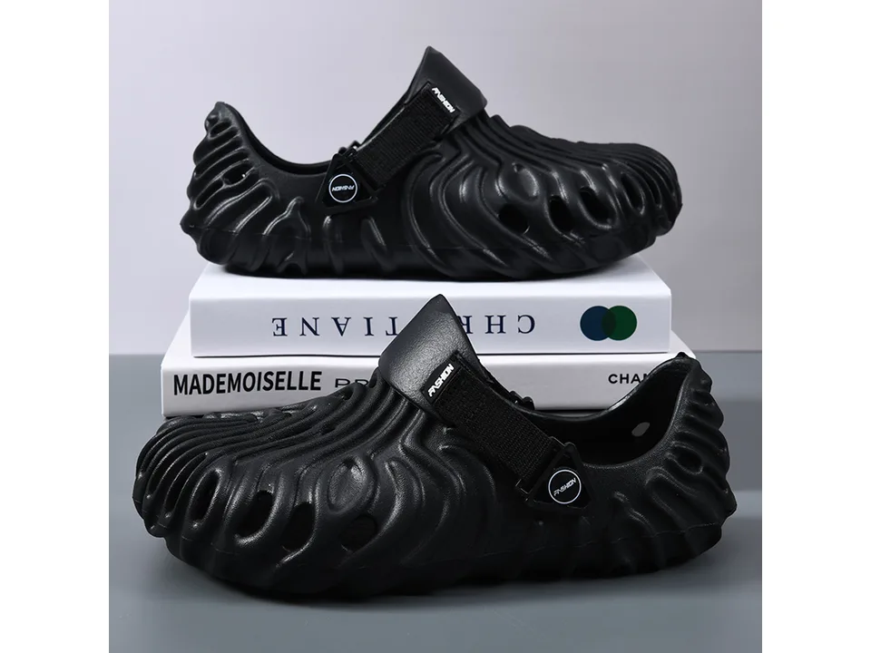 A pair of black textured EVA sandals with adjustable straps stacked on books.