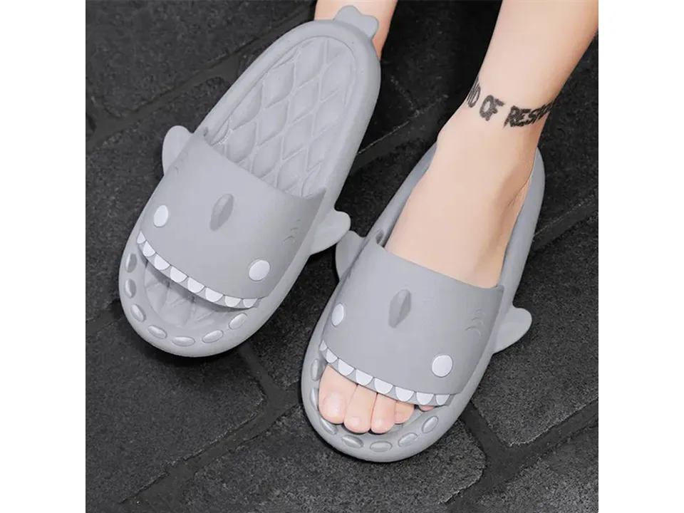 A person wearing grey shark-shaped slides.