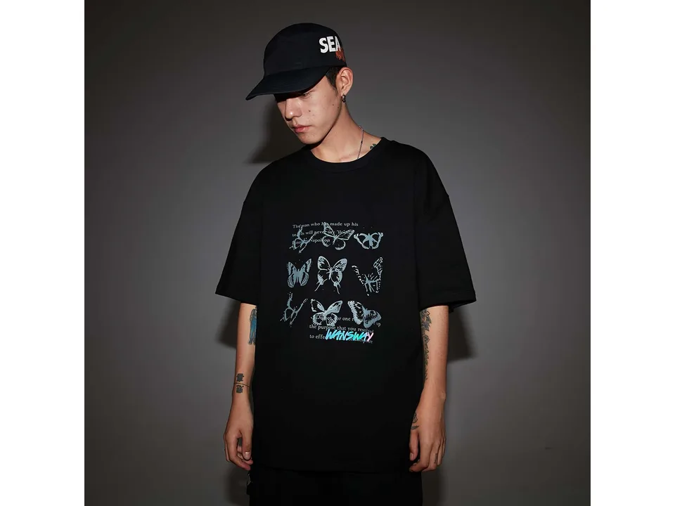 A model wearing a black oversized t-shirt with a butterfly graphic print.
