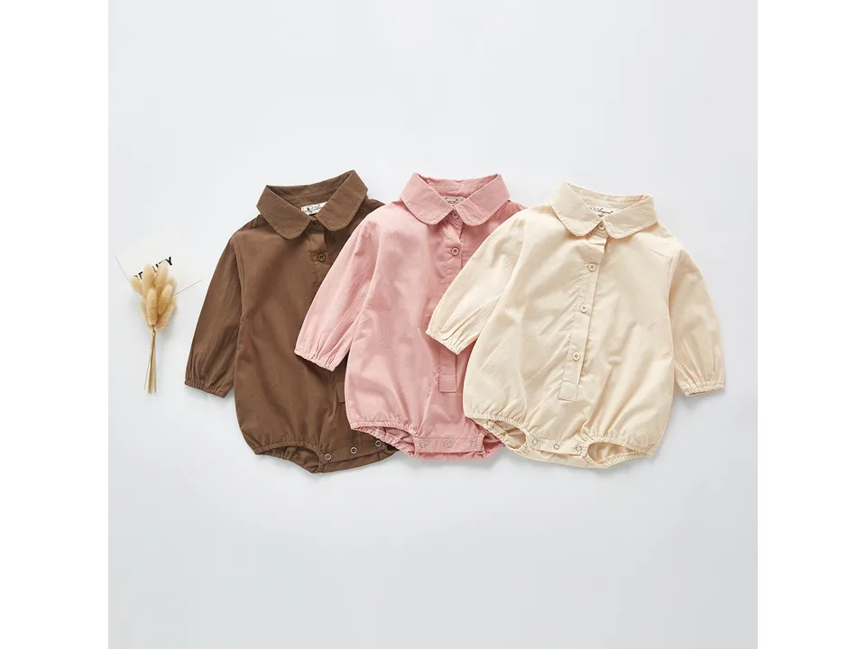 Three baby bodysuits in brown, pink, and beige laid out side by side.