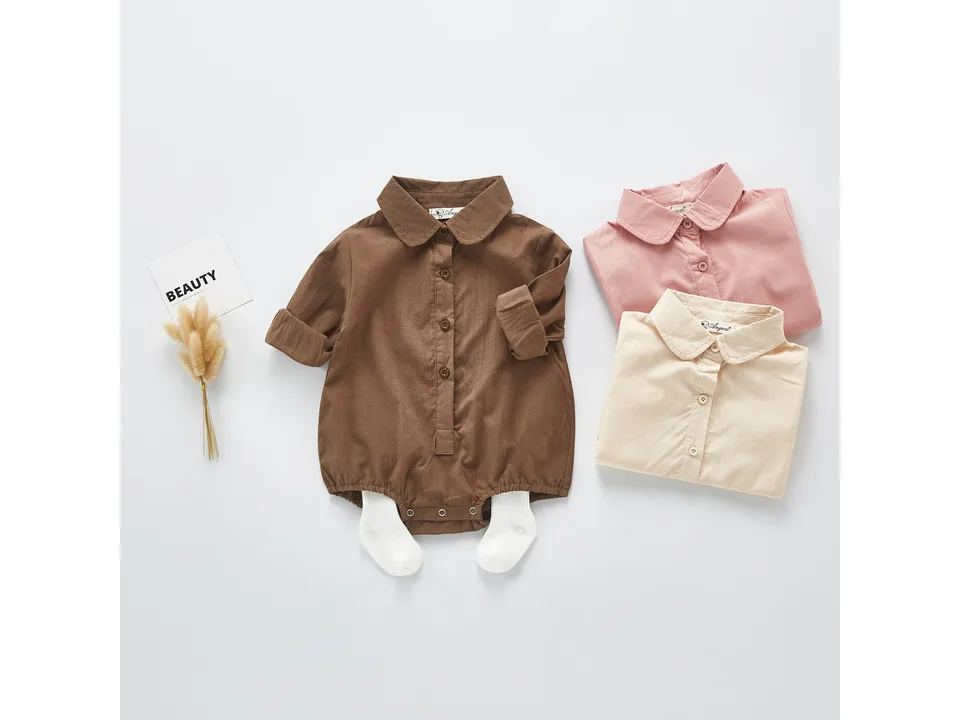 Brown baby bodysuit with white socks, next to folded pink and beige bodysuits.