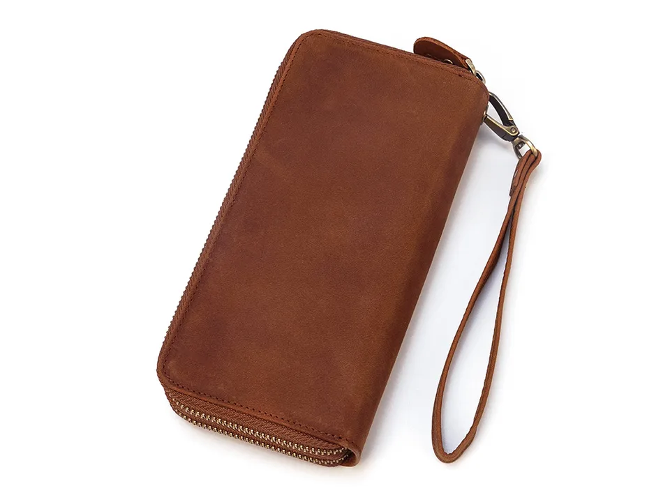Brown leather clutch bag with a wrist strap attached.