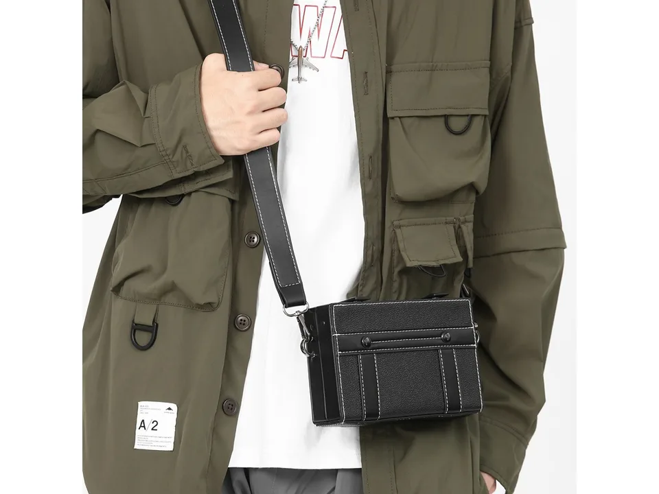 Close-up of a person wearing a black box-style crossbody bag.