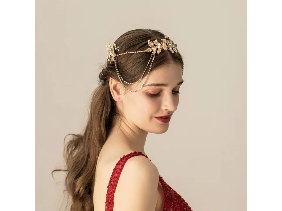 A woman wearing a gold floral bridal chain headband with rhinestone drapes.