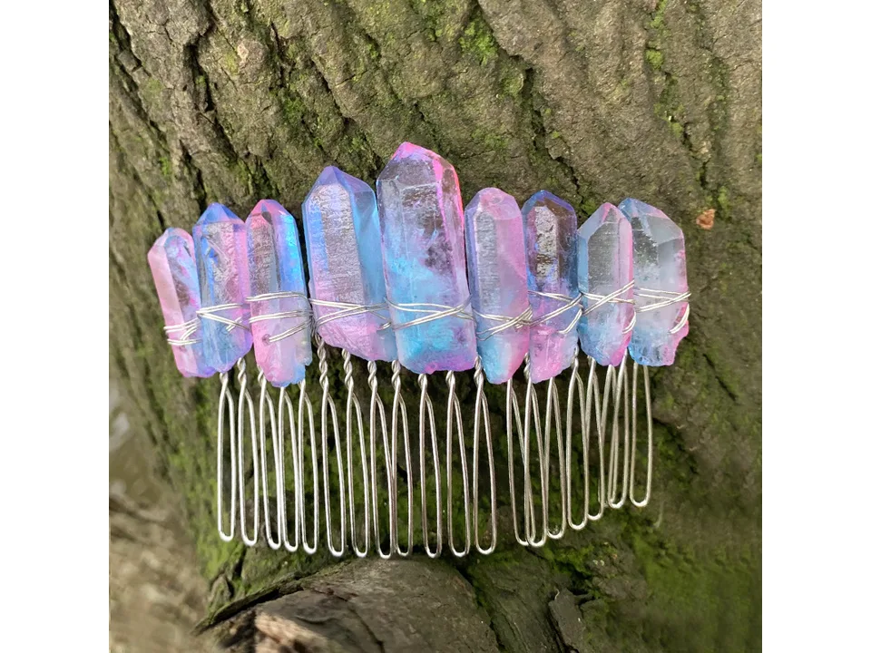 A pink and blue crystal hair comb resting against tree bark.