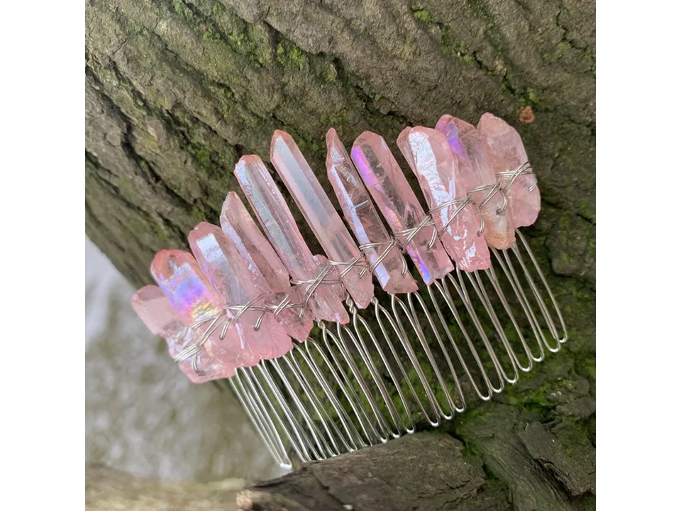 A pink crystal hair comb resting against tree bark.