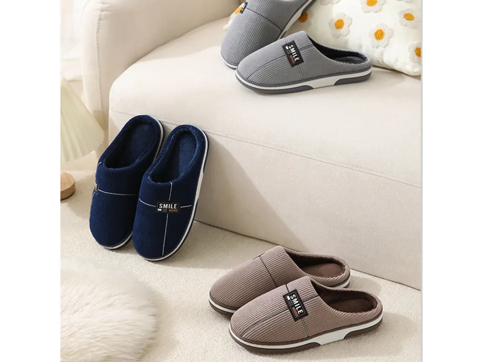 Three pairs of slippers in blue, grey, and brown displayed on a sofa.