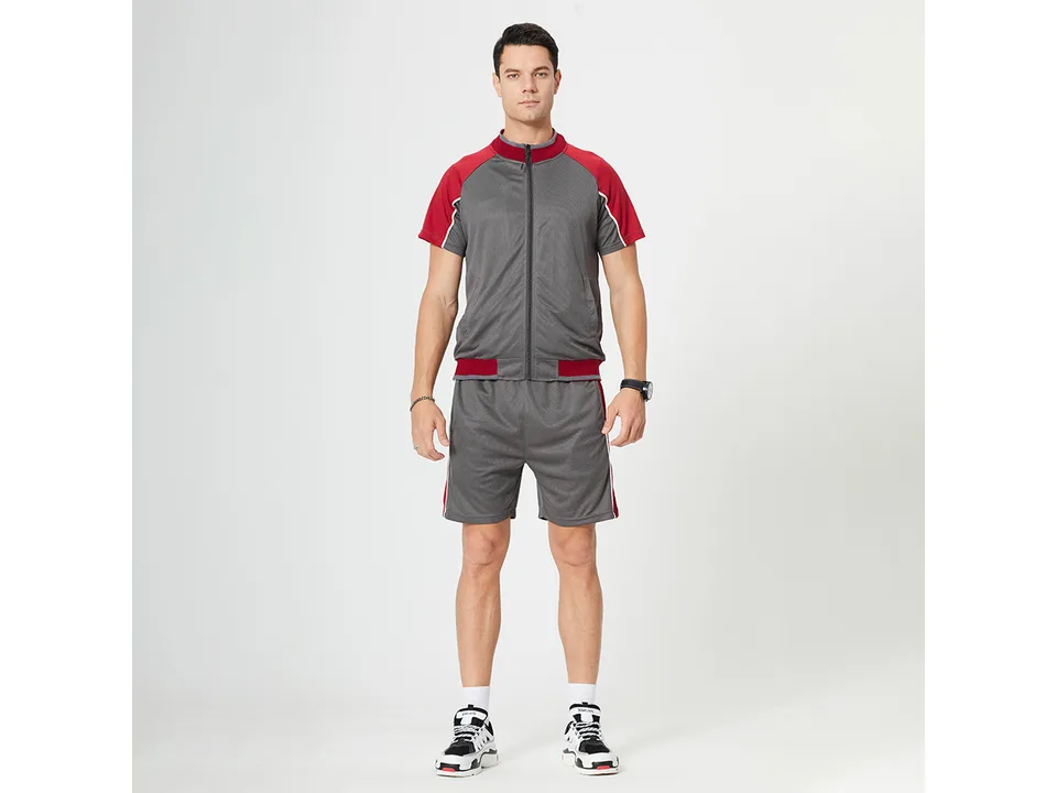 A man wearing a grey and red short-sleeve zip-up sports suit with matching shorts.