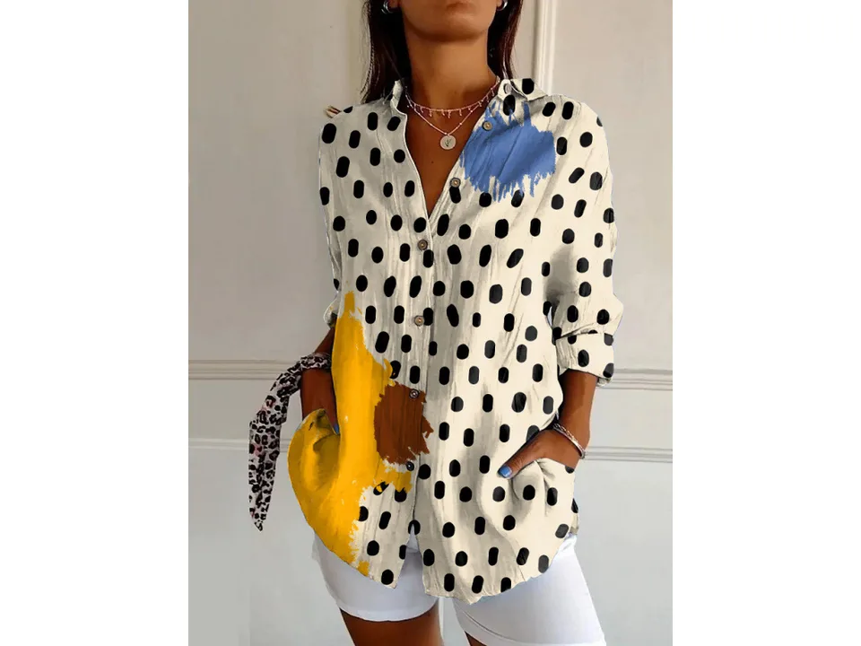 A woman wearing a long-sleeve button-down shirt with a black polka dot print and yellow accents.