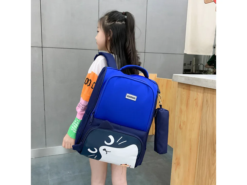 A child wearing a blue school backpack with a cat design.