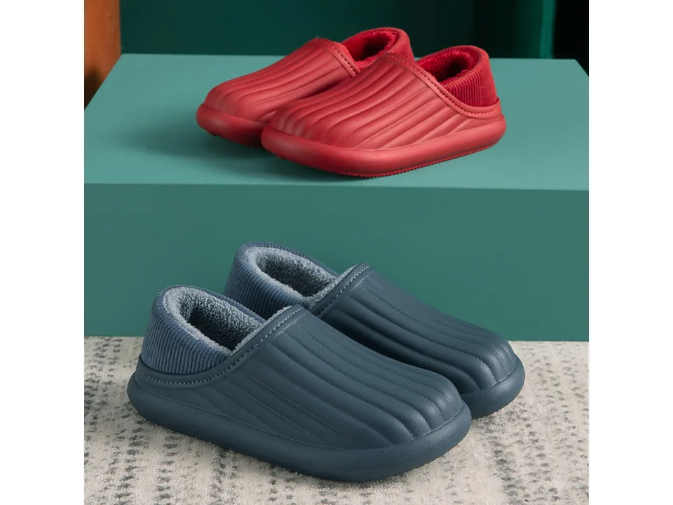 A pair of red slippers and a pair of blue slippers displayed on a green surface.