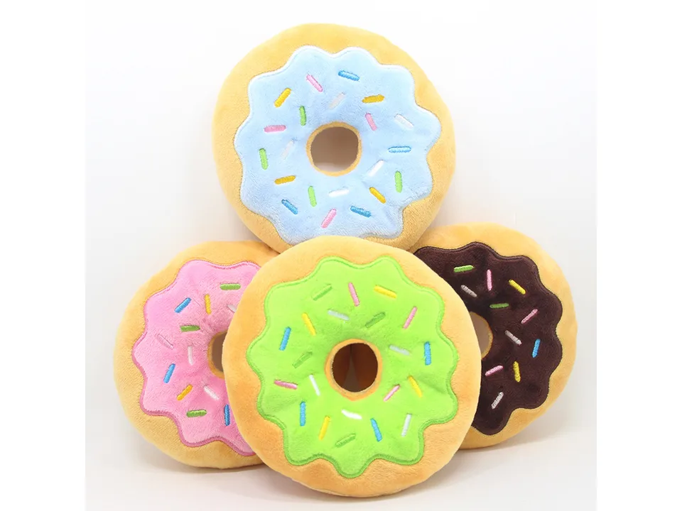 A group of four plush donut toys in pink, blue, green, and chocolate frosting colors.