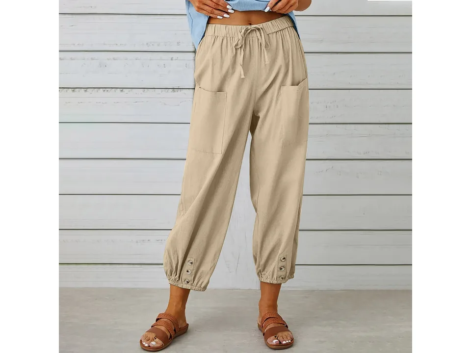 A woman wearing beige cropped wide-leg trousers with button details.