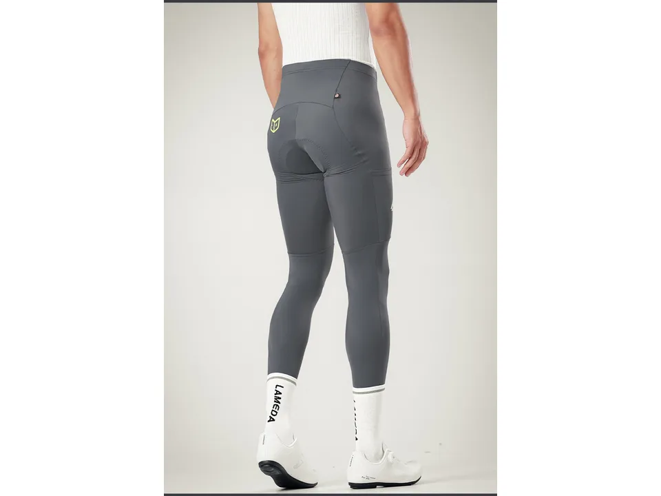 A man wearing grey cycling bib pants, viewed from the back to show the fit and details.