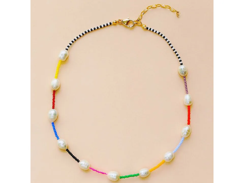 Rainbow baroque pearl choker necklace with colorful beads on a beige background.